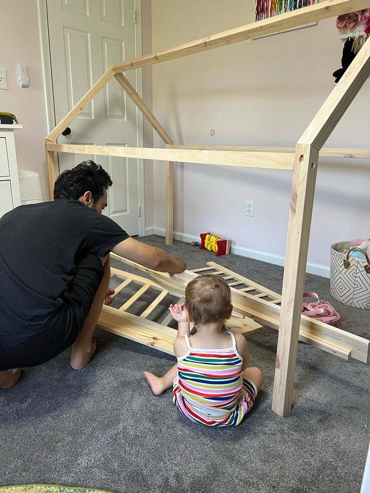 Parent assembling Aiden Toddler House Bed with Rails with toddler, showing easy setup and family-friendly design for Montessori-style bedrooms.