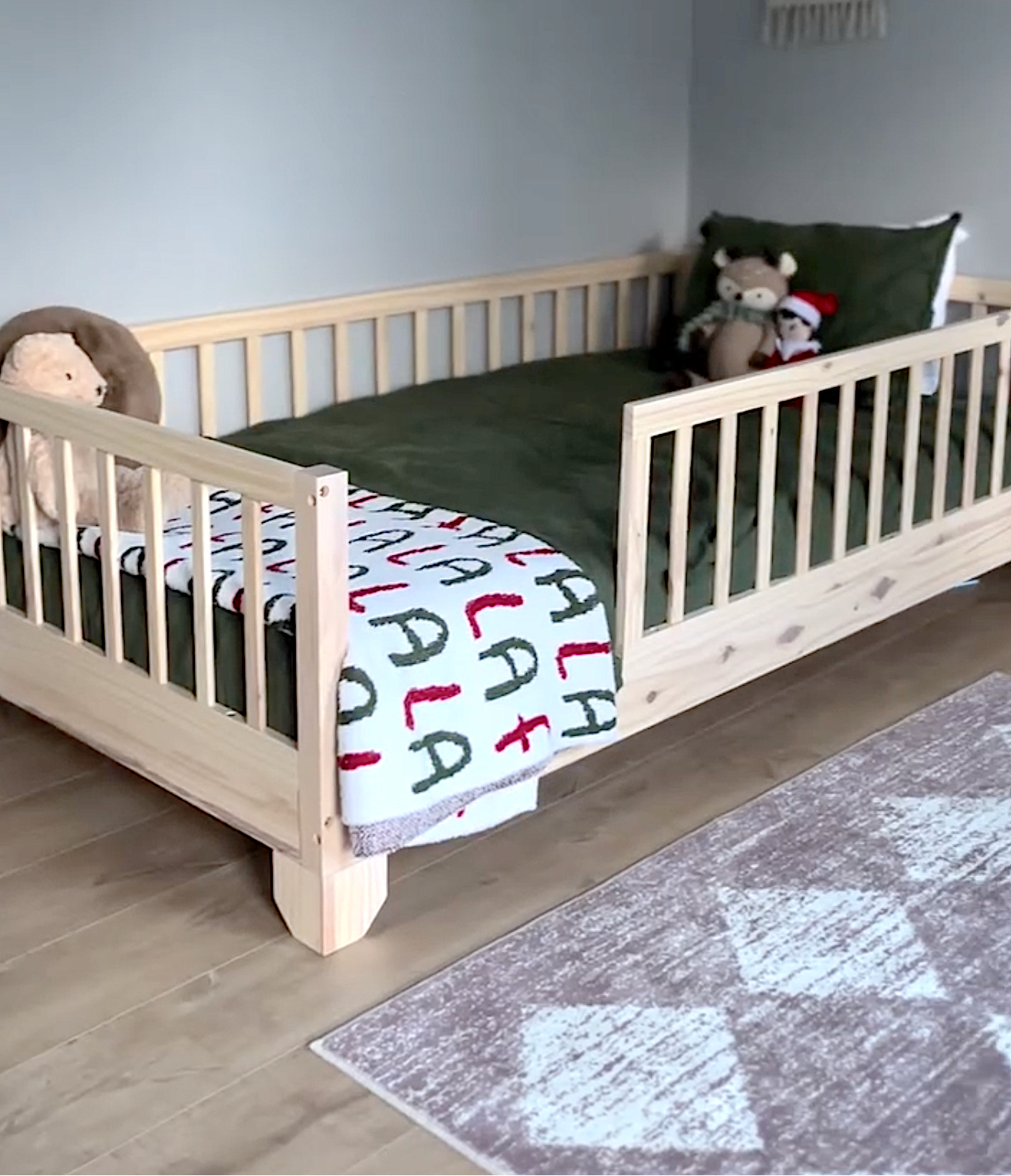 Children's Montessori Toddler Bedroom with a low wooden crib and colorful Christmas bedding