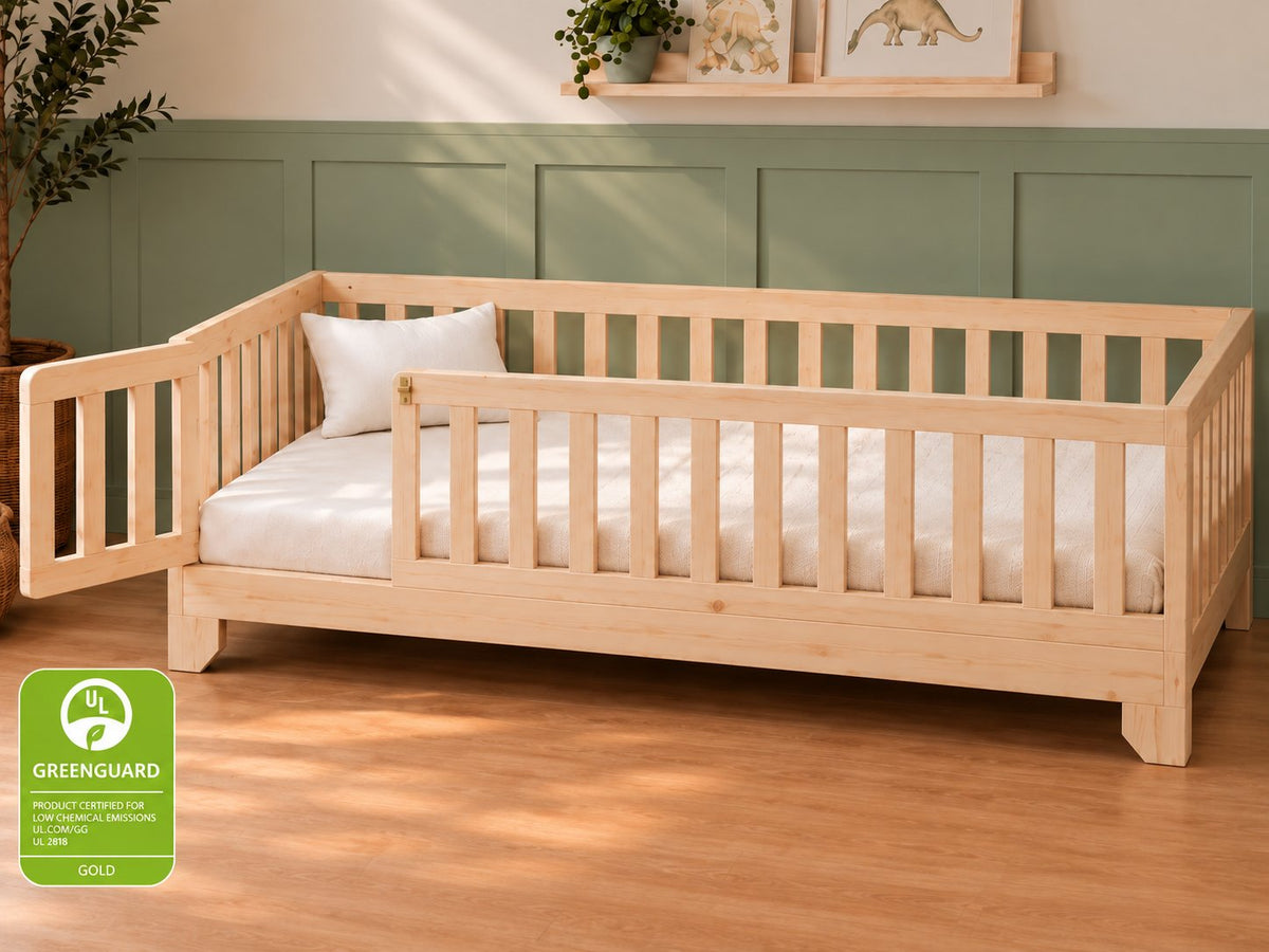 Luca Montessori twin size floor bed for toddlers with a natural finish, rails and a gate in a sage green bedroom.