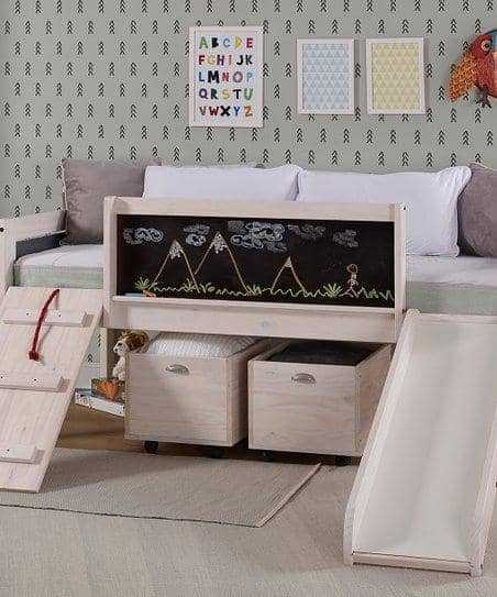 Oliver Low Loft Bed with Slide in natural wood finish featuring chalkboard panel, ladder, slide, and under-bed storage drawers in kids room.